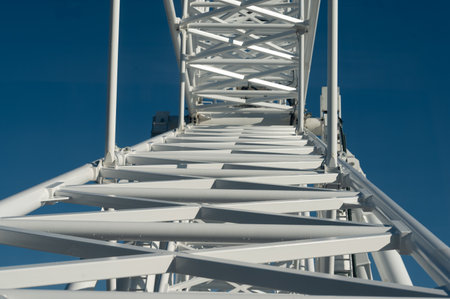 Exploring the intricate design of a colossal framework, sunlight glints off the white beams while a sense of height and engineering brilliance envelops the scene.の写真素材