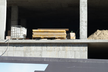 Workers gather materials like wooden beams and sand at a construction site, showcasing progress in...