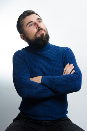 Thoughtful man with crossed arms looking upの写真素材