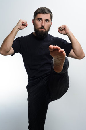 Man in black kicking forward with determined expression.の写真素材