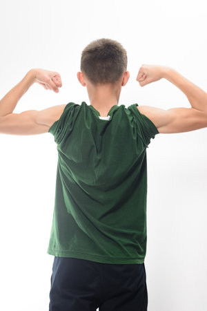 A rear view of a boy showing off his biceps. He's wearing a casual dark green t-shirt and dark...