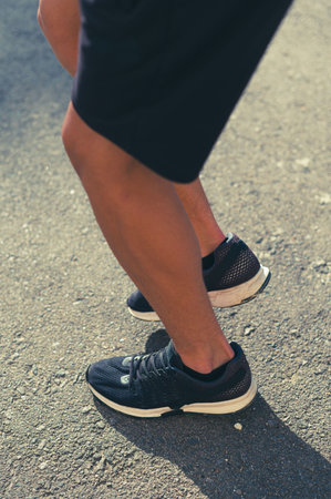 Runner stretching on asphalt road.  Focus on athletic shoes.の写真素材