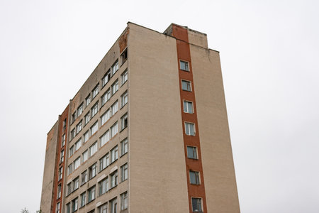 A tall high-rise structure reveals peeling paint and bare windows as it looms against a dreary...