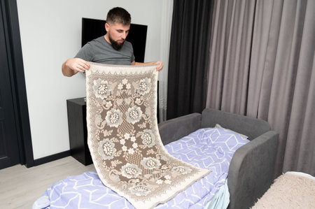 A person carefully unfolds a stunning lace tablecloth in a modern room, blending craftsmanship and artistry. The soft evening light enhances the details and textures.の写真素材