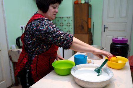 A woman in a colorful apron prepares a delicious meal in her bright kitchen, surrounded by fresh ingredients and cheerful bowls, embodying the essence of home cooking.の写真素材