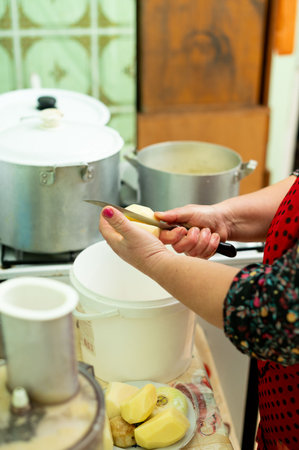 A person peels potatoes with care in a charming kitchen while pots simmer, capturing the essence of homemade cooking and family gatherings on a cozy afternoon.の写真素材