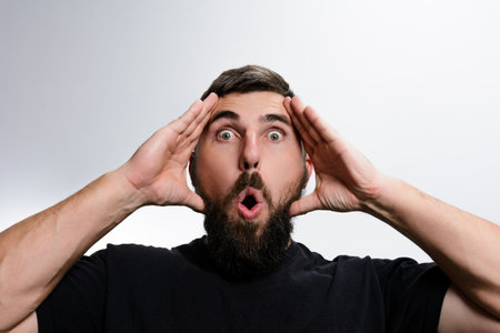 Surprised man with beard and open mouth against white backgroundの写真素材