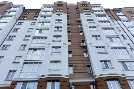 Tall urban structure rises into the evening sky, featuring a vibrant facade of brown and white....