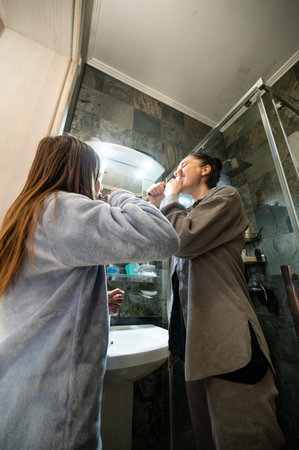 Two friends enjoy a shared moment in the bathroom, brushing their teeth together in a bright and inviting space, embracing the start of a new day with laughter and friendship.の写真素材