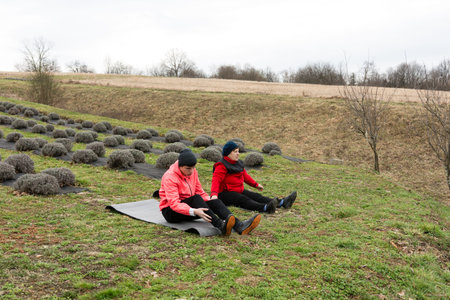 Two friends take a break on a grassy slope, chatting and relaxing amidst rows of lavender. The...