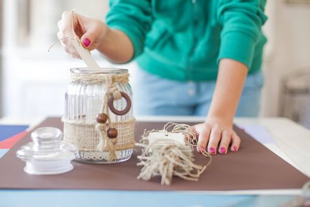 Young woman make scrapbook of the papers on the table using antique tools for cutting paper. Hand made photo album.Shallow depth of fieldの写真素材