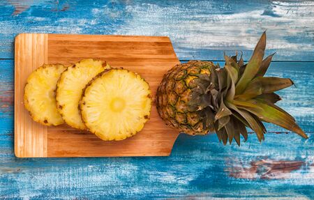 Pineapple on the blue vintage wooden plate with circular cut up piecesの写真素材
