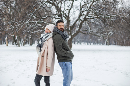 Happy loving couple walking in winter park enjoying snowの写真素材