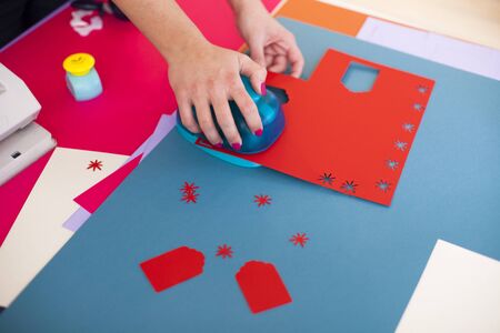Young woman make scrapbook of the papers on the table using antique tools for cutting paper. Hand made photo album.Shallow depth of fieldの写真素材