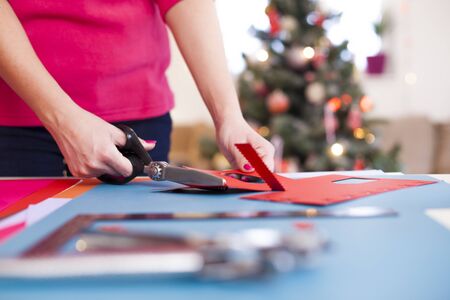 Young woman make scrapbook of the papers on the table using antique tools for cutting paper. Hand made photo album.Shallow depth of fieldの写真素材