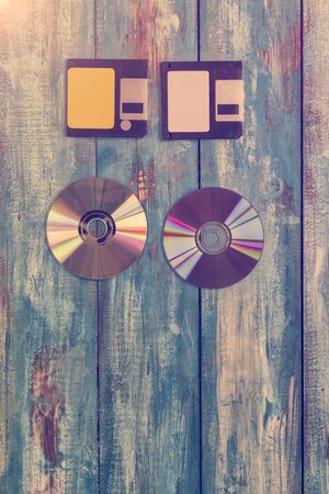 Floppy disk and compact disc on vintage wood boardの写真素材