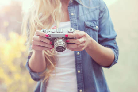 Outdoor smiling lifestyle portrait of pretty young woman with retro camera on terasseの写真素材