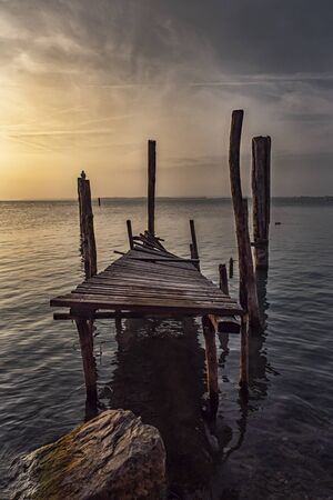 Old ruined pier on Lake Garda at sunsetの写真素材