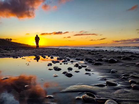 Woman walking on a beach at sunsetの写真素材