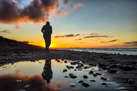 Woman walking on a beach at sunsetの写真素材