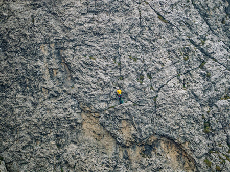 Lonely climber in yellow shirt on a mountain wallの写真素材