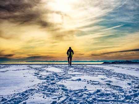 Man walking in the snow at sunsetの写真素材