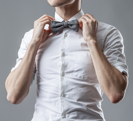 Stylish man in a white classic shirt correcting bow tie. The official style of clothes.の写真素材