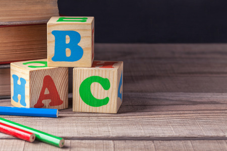 Children's wooden blocks with letters and colored pencils lying on a wooden table. Closeup.の写真素材