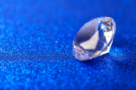 Grand royal pure diamond on blue sparkling sequins background, macro . Big brilliant closeup.の写真素材