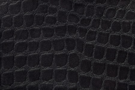 Black background from a soft upholstery textile material, closeup. Fabric with pattern imitating...