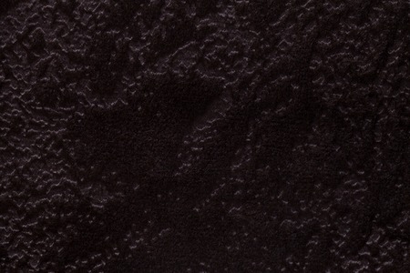 Dark brown background from a soft upholstery textile material, closeup. Black fabric with natural...