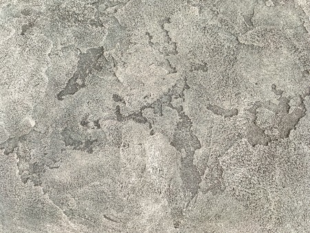 Old light brown wall covered with shabby uneven plaster. Texture of vintage gray stone surface, closeup.の写真素材