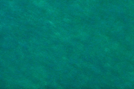 Construction of dark green turquoise background with navy blue spots of felt fabric, closeup. Texture of woolen matt textile. Cloth backdrop.の写真素材