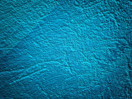 Old navy blue wall covered with shabby uneven plaster. Texture of vintage turquoise stone surface with vignette.の写真素材