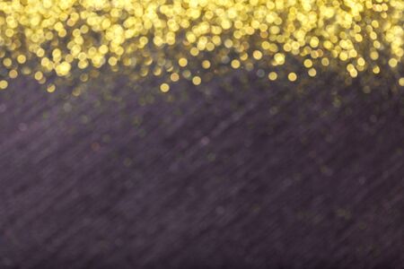 Black blurred background for Christmas greeting card with golden sequins lights bokeh. Blackboard...