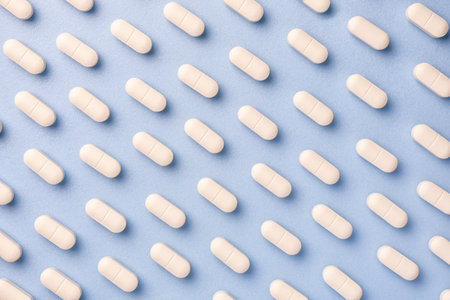 Blue medicine background with white pills and tablet, macro. Drug production backdrop. Medical...