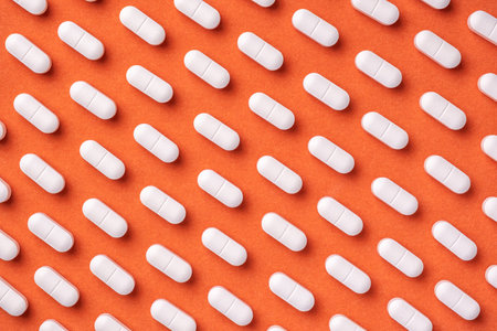 Orange and red medicine background with white pills and tablet, macro. Drug production backdrop....
