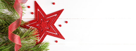 Christmas vintage white wooden background with red star, shiny ribbon and green tree bunch of fir...