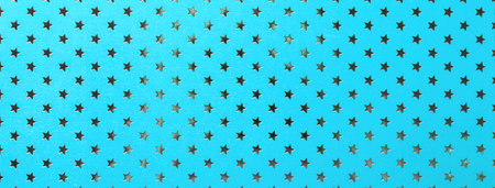 Light blue background from metal foil paper with pattern of silver stars, closeup. Texture of cerulean metallized wrapping holiday backdrop.の写真素材