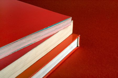 Stack of books with red covers on red backgroundの写真素材