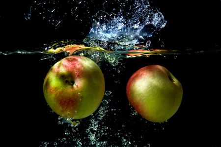 Apples falling to the water with splash and dropsの写真素材