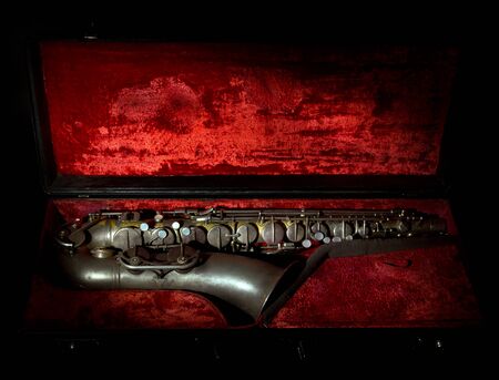 Old saxophone in a case with red backgroundの写真素材