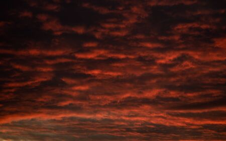 Dark Red Orange and Yellow Clouds Hang Over the Landscape