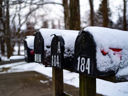 Closed mailboxes in a line with snow covering them after a storm.