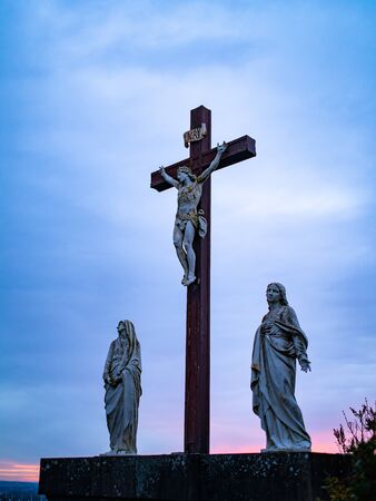 A Crucifix Statue With Two Statues of Woman Alongsideの写真素材