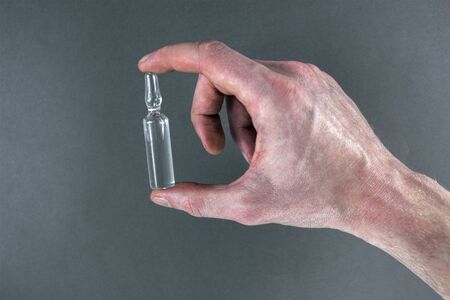 ampoule in a hand on a light gray background