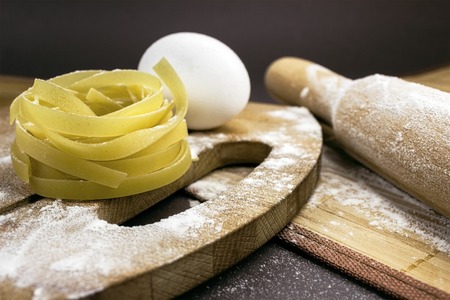 Raw homemade pasta and ingredients for pasta on wooden background