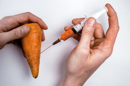 Genetically modified organism - ripe carrot with syringes on white backgroundの写真素材