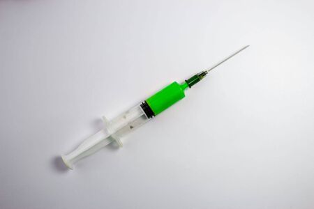 Syringe filled with green medication on a white background with space for textの写真素材
