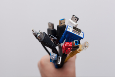 Hand holding a bunch of pc computer cables with different connectorsの写真素材